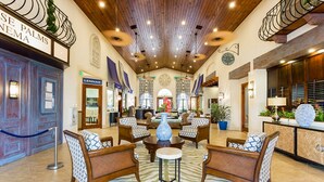 A lobby with wooden ceiling, seating area, reception desk, and a sign reading "SE PALMS NEMEA". - Paradise Palms 8963 D (Kissimmee)