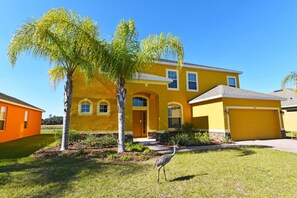 Une maison jaune avec un garage et un arbre dans le jardin.