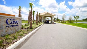 A hotel entrance with a sign reading "The Cove at Storey Lake," palm trees, and a covered walkway leading to the parking area. - Storey Lake 3131 (Kissimmee)