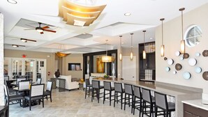 A spacious hotel lobby with a central bar area, seating arrangements, and a modern ceiling design. - Solterra 4380 (Davenport)