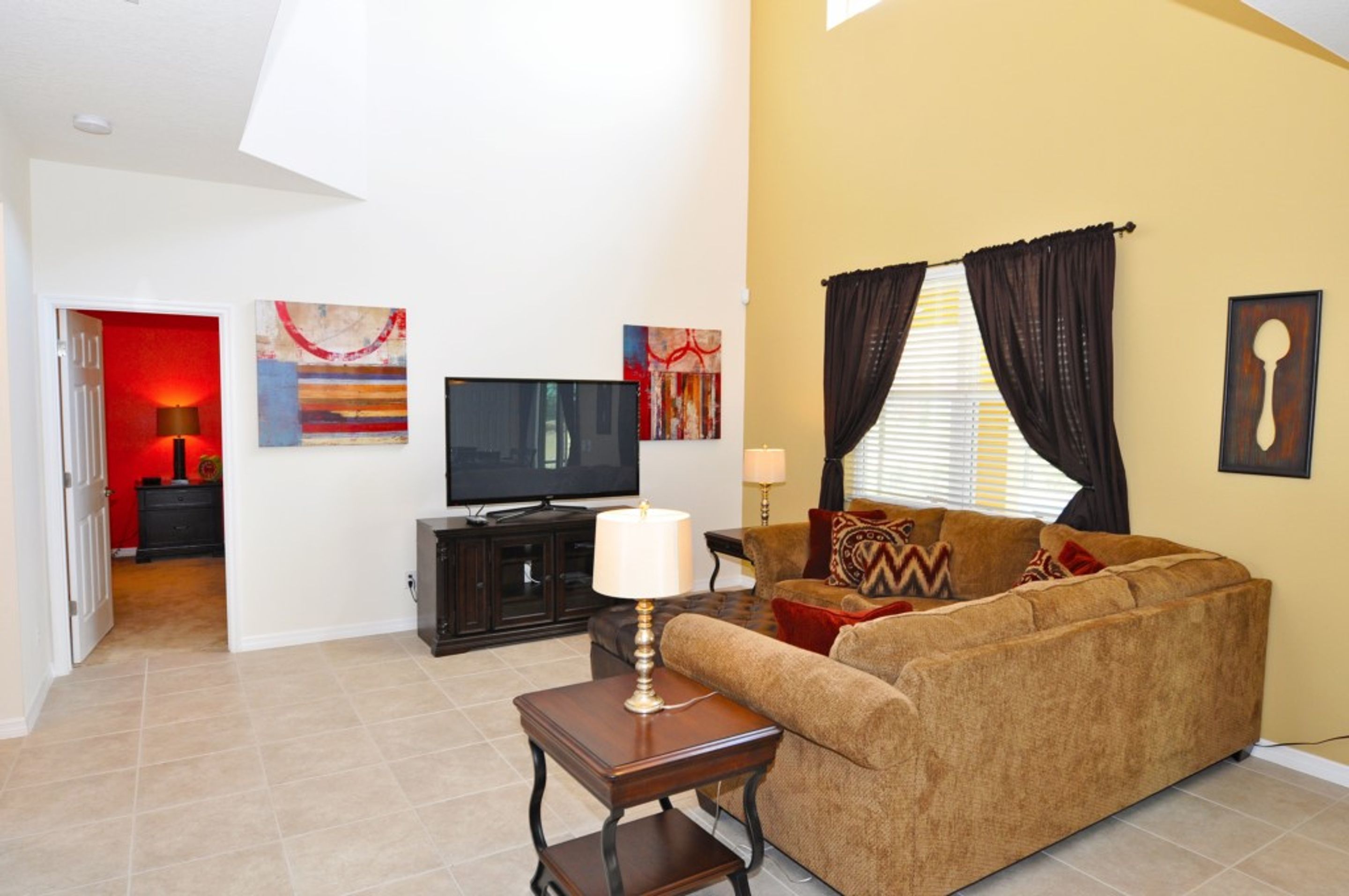 A living room with a sofa, a TV, and artwork on the walls.