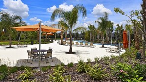 A pool area with lounge chairs and umbrellas, surrounded by palm trees and a clear sky. - Solterra 4380 (Davenport)