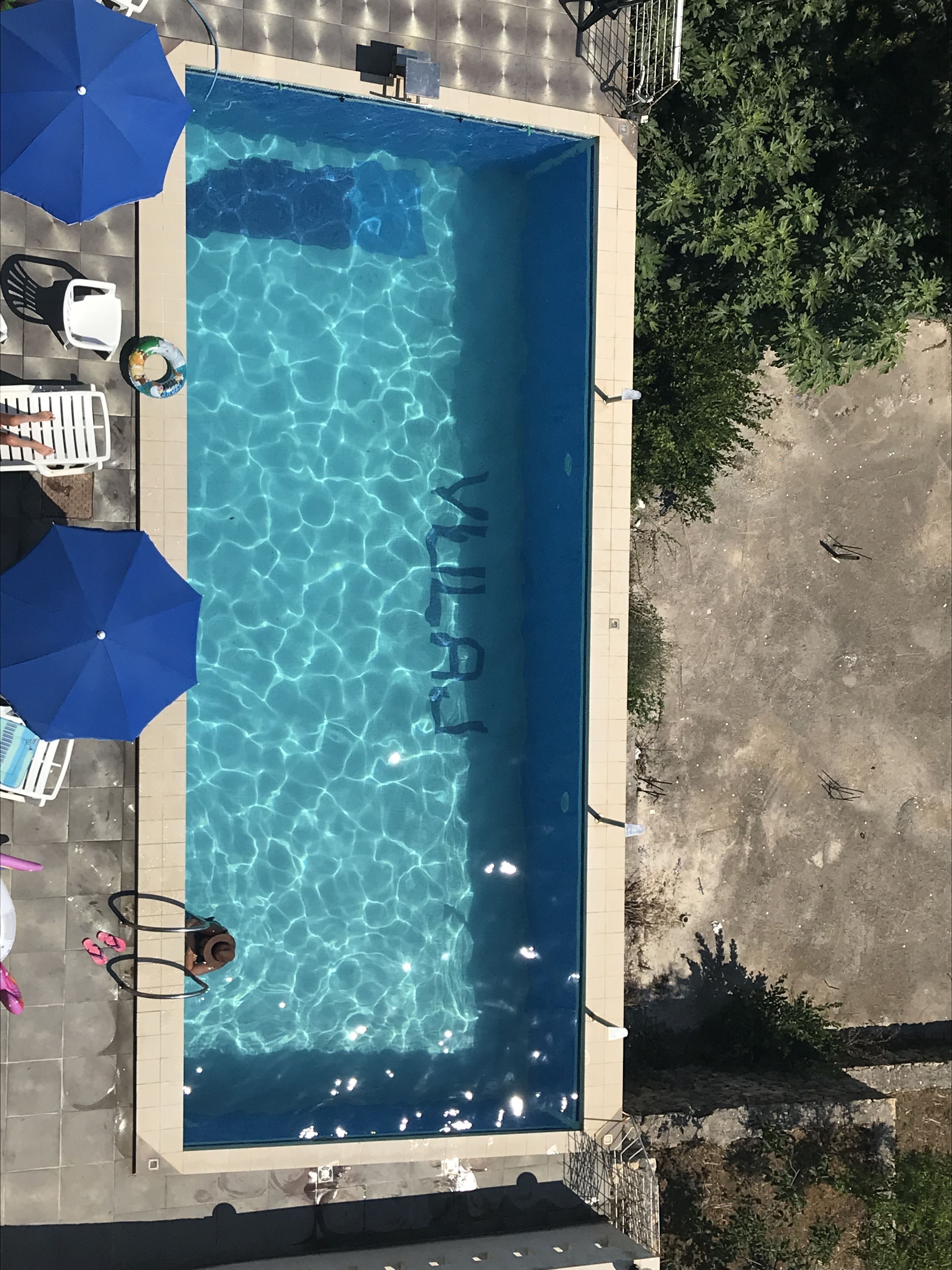 Una piscina rectangular con agua azul cristalina, rodeada por una solana con baldosas.