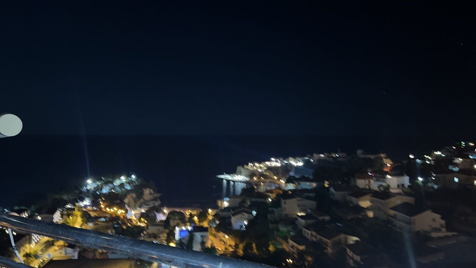 Vista nocturna de un asentamiento en una ladera con edificios iluminados.