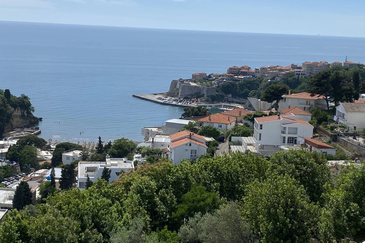 A coastal town with buildings, a pier, and a clear view of the sea.