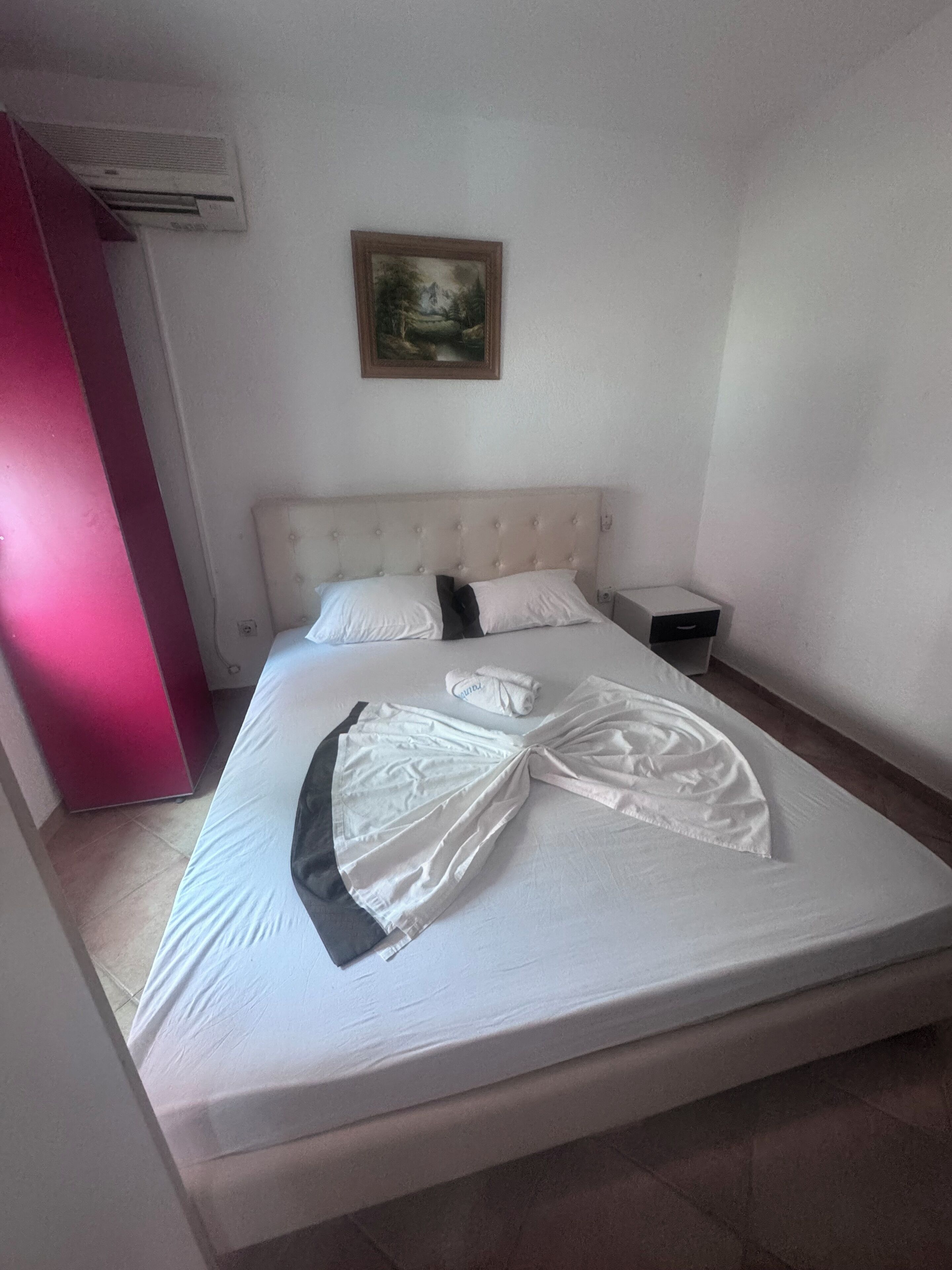 A neatly made bed with a white duvet, a folded towel, and a neatly arranged pillow.