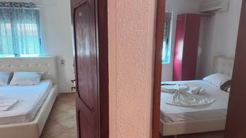 A hotel room with two beds, a wooden door, and an air conditioning unit.