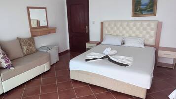 Una habitación de hotel con una cama, un sofá, una mesita, un calentador, una puerta y un cuadro en la pared.