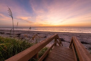 Walk along the beach on a weathered boardwalk leading to the ocean.