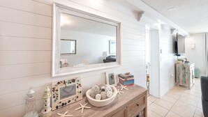 Una habitación con un aparador de madera, un espejo y una mesita con adornos.