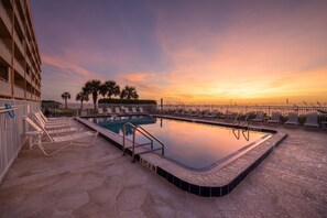 Relax by the pool surrounded by lounge chairs and a low fence, offering a safe and peaceful atmosphere.