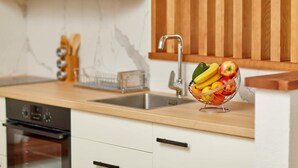 A kitchen with a wooden countertop, a stainless steel sink, and a fruit bowl.