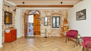 A room with a wooden herringbone floor, a red sofa, a ladder, and a stone wall.