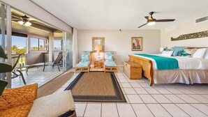 Una habitación de hotel con cama, escritorio, dos sillas, una mesa y un balcón con vistas.