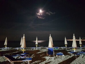 A beach with rows of sun loungers and umbrellas under a night sky with a visible moon. - LUXURY HOLIDAY HOUSE FRONT OF SEA FORMIA VINDICIO (Formia(LT))