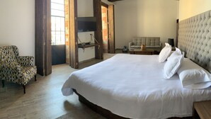 Une chambre à coucher avec un grand lit, un fauteuil à motifs, un canapé et une étagère en bois.