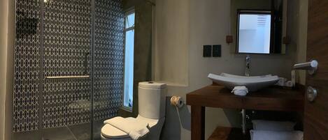 Une salle de bain comprenant des toilettes, un lavabo et un espace douche.