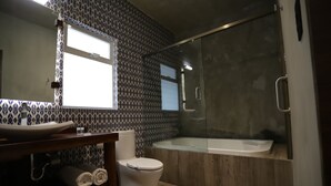 Une salle de bain avec un meuble-lavabo en bois, des toilettes, une baignoire et un espace douche.