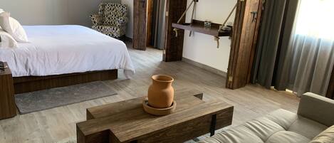 Un dormitorio moderno con cama, sofá, mesa de centro de madera y un sillón estampado.