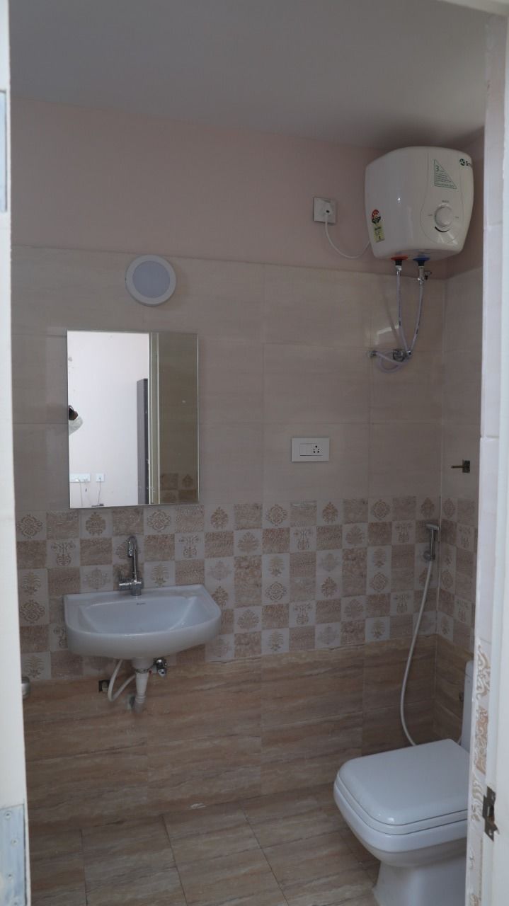 A bathroom with a sink, toilet, and a water heater mounted on the wall.