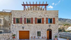 Un bâtiment en pierre doté d’une pergola en bois, d’une porte en bois et d’un garage.