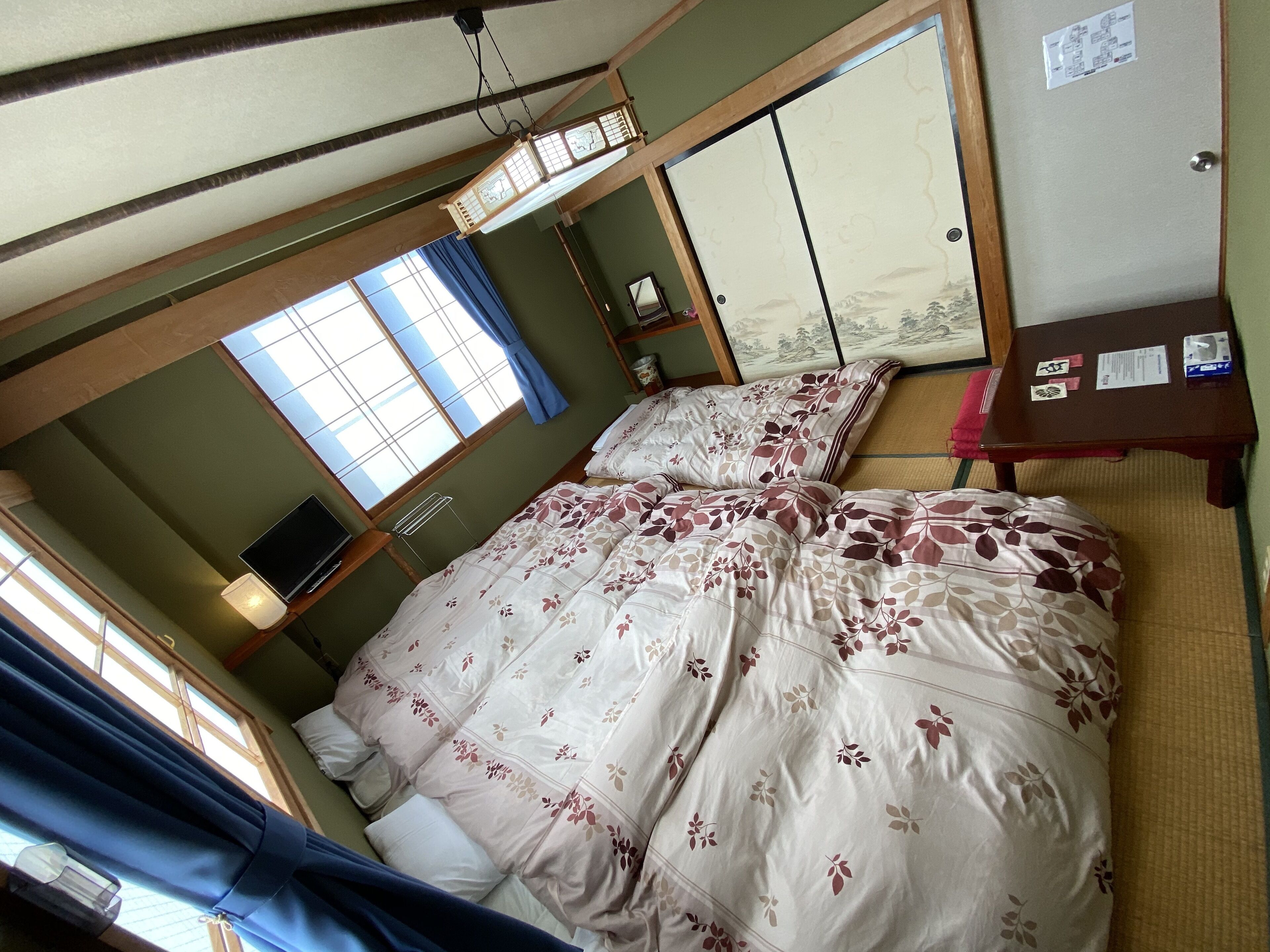 A bedroom with a bed, a desk, a chair, a window, and a sliding door.