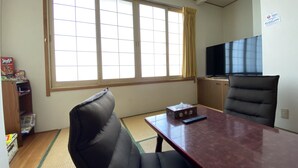 A hotel room with a large window, a television, a desk, and a sofa.