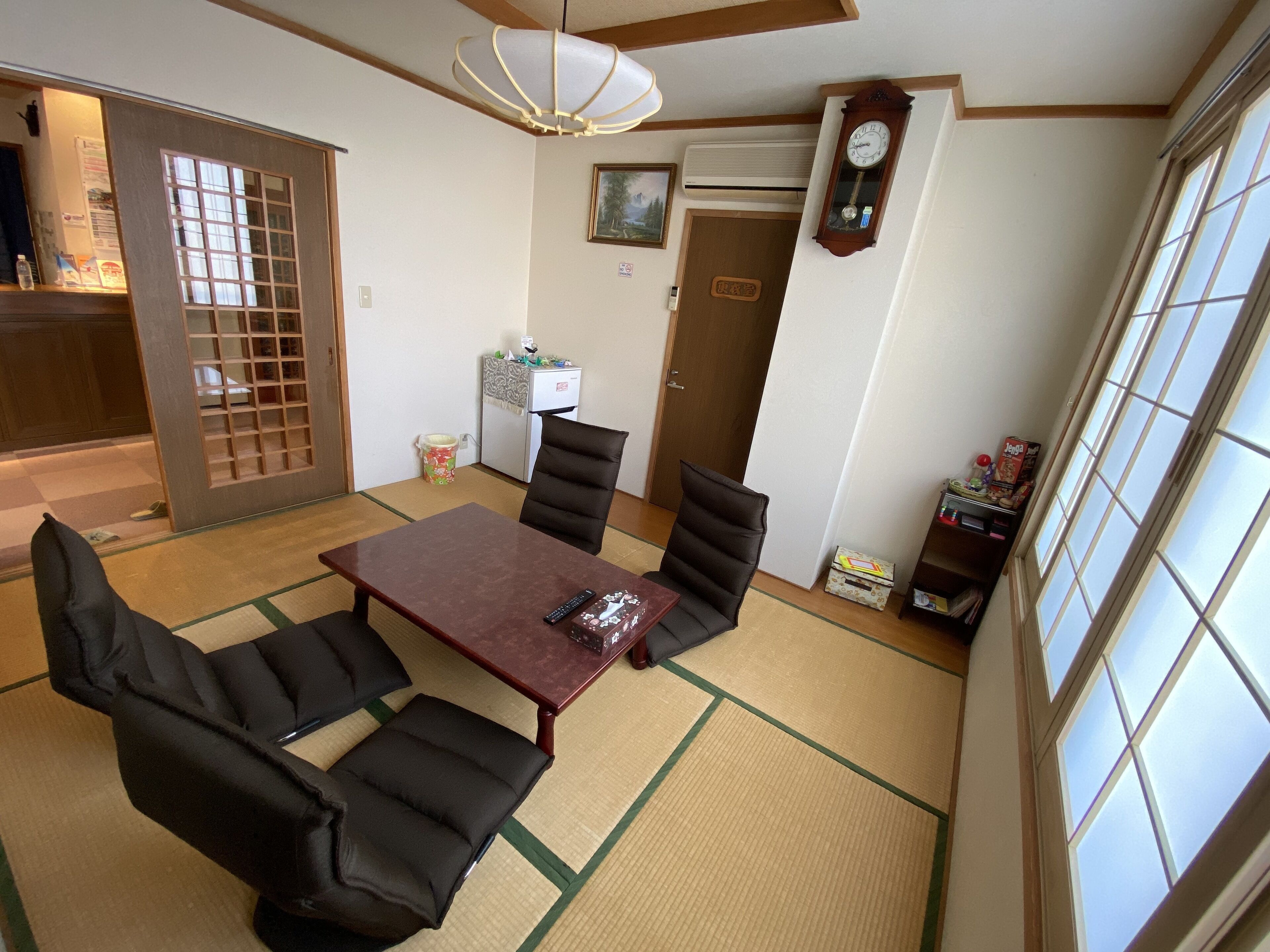 Una habitación tradicional japonesa con suelo de tatami, una mesa baja y asientos acolchados negros.