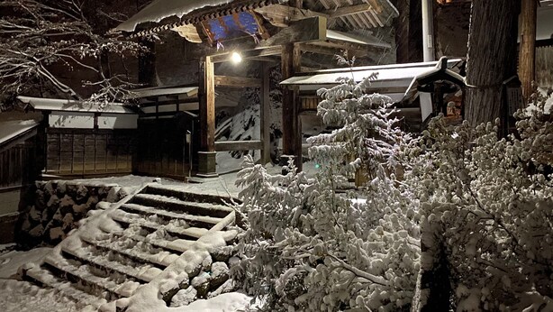A traditional Japanese building with a snow-covered entrance and steps leading up to it.