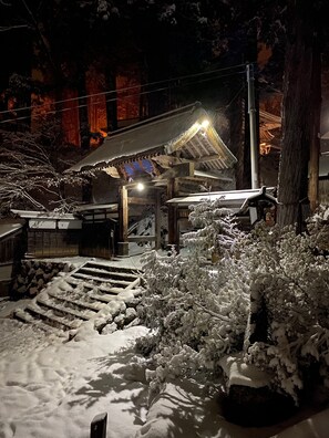 Un edificio japonés tradicional con una entrada cubierta de nieve y escalones que conducen a él.