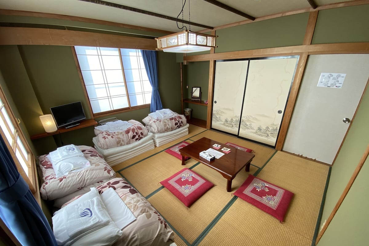 Een traditionele Japanse kamer met tatami vloeren, een lage houten tafel en futonbedden.