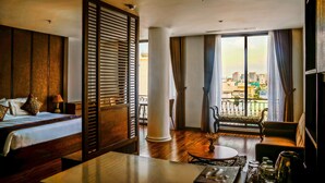 A hotel room with a bed, a desk, a chair, a balcony with a view of the city, and a large window with curtains. - Dong Duong Hotel (Da Nang)