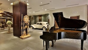 A grand lobby with a black grand piano, a vintage car, and a decorative column. - Dong Duong Hotel (Da Nang)