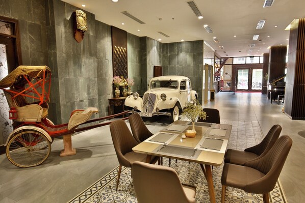 A dining area with a vintage car and a horse-drawn carriage.