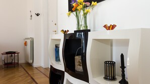 A modern living room with a white fireplace, a black vase with flowers, and a black candle holder. - Bright, stylish, renovated Flat near Villa Borghese (Roma)