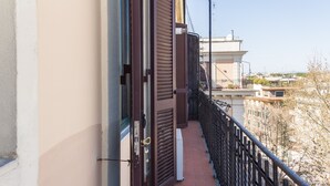 A balcony with a metal railing, a brown shutter door, and a view of buildings in the background. - Bright, stylish, renovated Flat near Villa Borghese (Roma)
