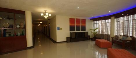 A spacious lobby with a chandelier, a fireplace, and a seating area with a sofa and ottoman.