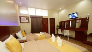A hotel room with two beds, a desk, a television, and a mirror. - Hacasi Hotel (Tacloban)