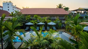A hotel with a swimming pool surrounded by palm trees and lounge chairs. - RATA  Boutique (Siem Reap)