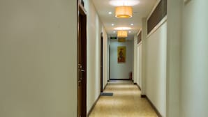 A hotel hallway with wooden flooring, a fire extinguisher, and a door on the left. - RATA  Boutique (Siem Reap)