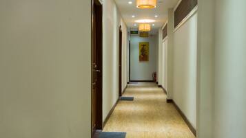A hotel hallway with wooden flooring, a fire extinguisher, and a door on the left.