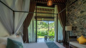 A bedroom with a bed, a bench, a lamp, and a view of the outdoors. - Aravinda Resort (Nam Hoa Lu)