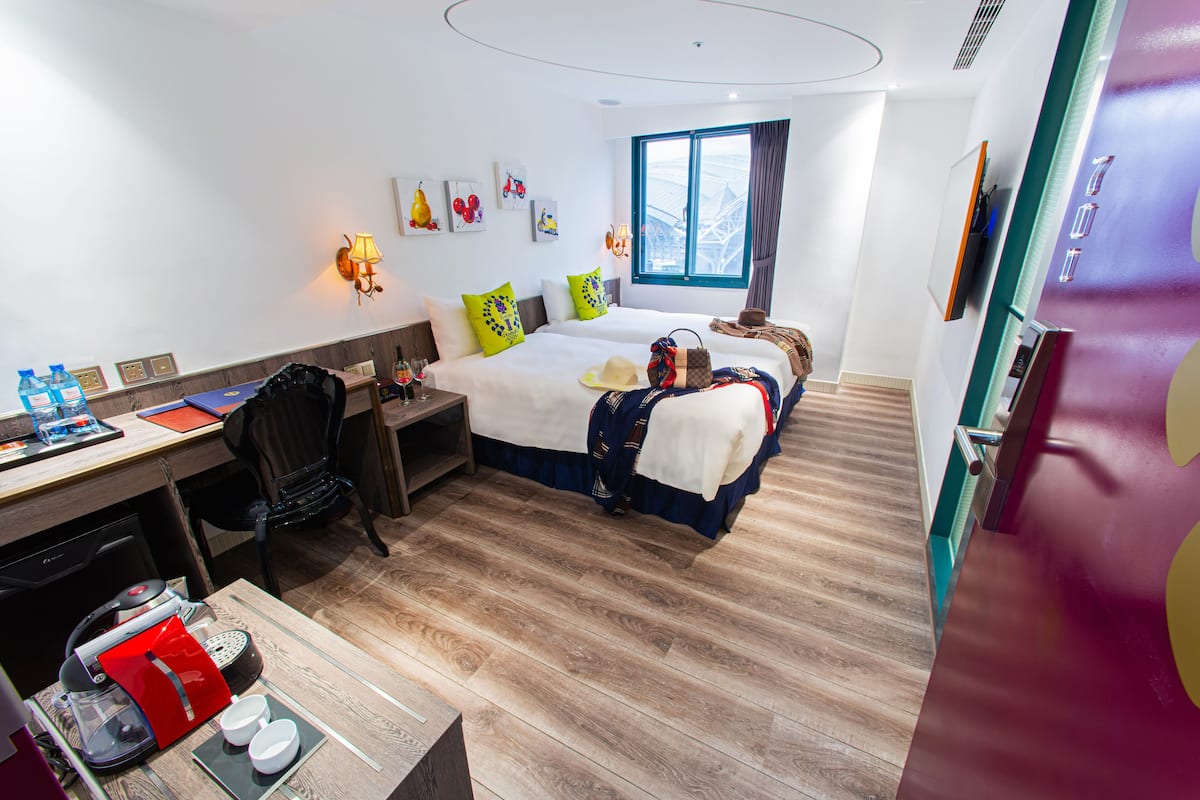 A hotel room with a bed, desk, chair, and a window with a view.