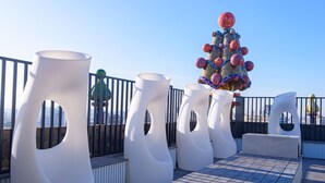 Een terras op het dak met moderne witte stoelen en een decoratieve kerstboom.