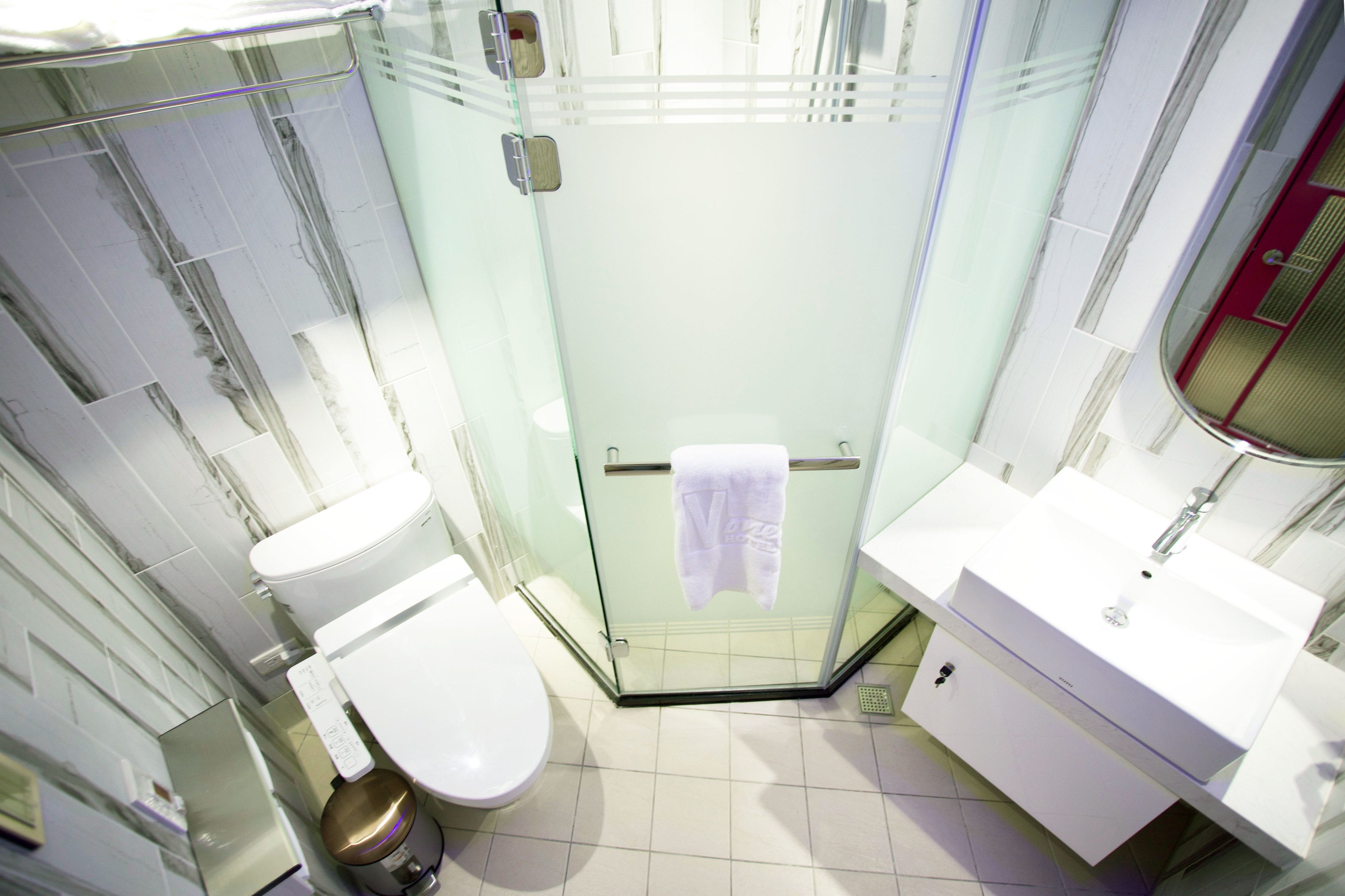 A modern bathroom with a glass shower enclosure, a white toilet, and a white sink with a mirror above it.