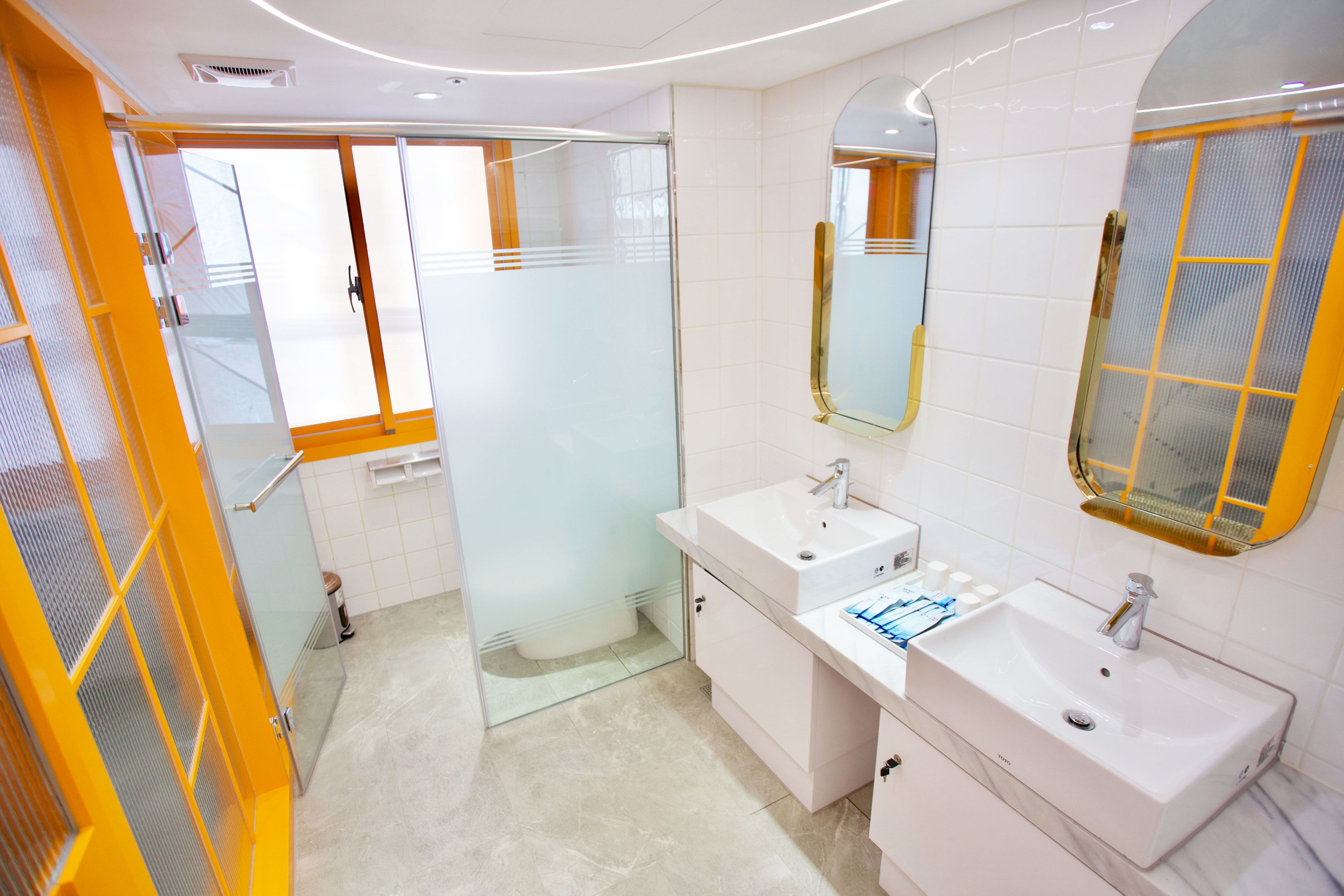 A modern bathroom with two sinks, a mirror, and a glass shower enclosure.