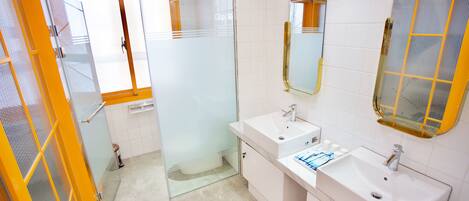 A modern bathroom with two sinks, a mirror, and a glass shower enclosure.