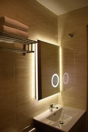 A modern bathroom with a large mirror, a sink, and a towel rack.