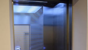 A narrow elevator with a geometric floor pattern and a reflective glass door. - MM Hotel at Sunway (Petaling Jaya)