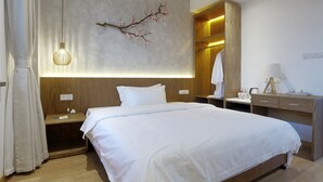 A modern hotel room with a large bed, wooden nightstands, a wall-mounted branch decoration, and a bedside table with a lamp. - The Moment We Met (Changzhou)
